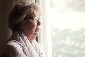 An elderly lady looking out of the window
