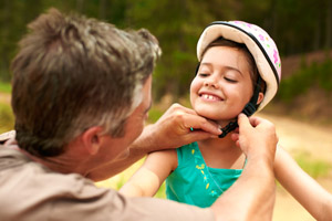 A caregiver putting on a bike helmet on a child