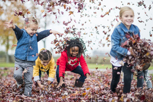 Four kids playing with leaves in a park