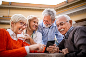 a group of elderly men and women smiling while looking at a phone