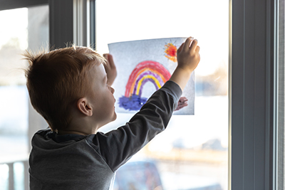 young child with a drawing of a rainbow
