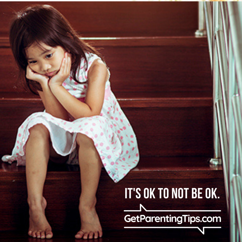 Young child sitting on stairs resting her face in her hands. Text: It's OK to not be OK. GetParentingTips.com