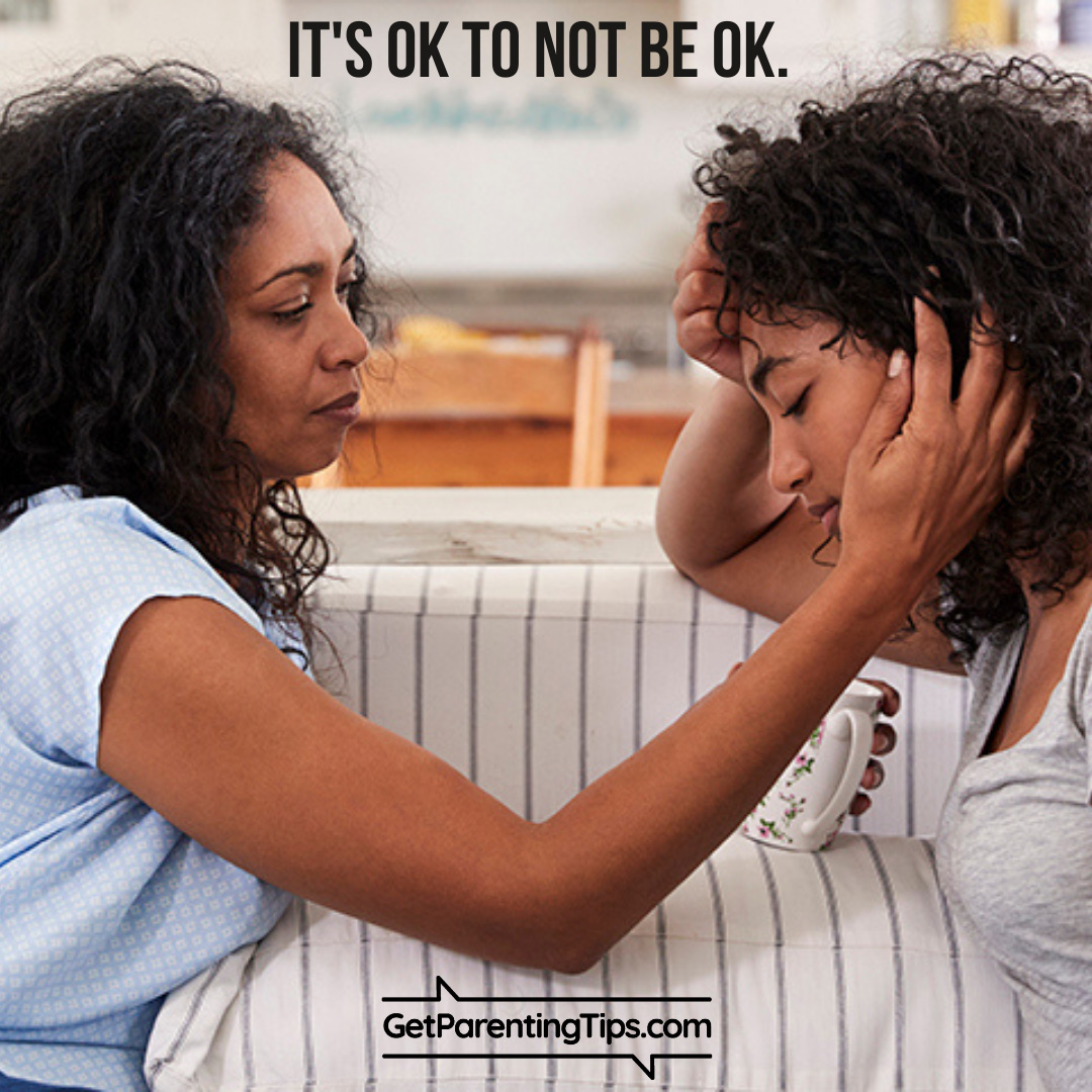 Mom caressing and consoling her teenage daughter. Text: It's OK to not be OK. GetParentingTips.com
