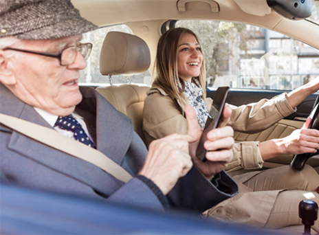 A women volunteer driving an elderly gentleman.