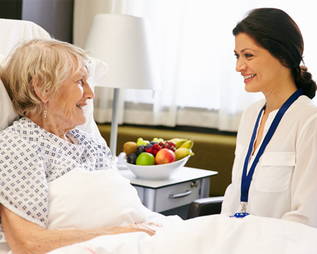 A volunteer sitting with an elderly lady in a hospital